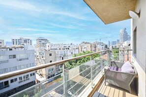 Ein Balkon mit einem Korbstuhl und Blick auf eine Stadtlandschaft.