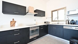 A modern kitchen with black cabinets, a stainless steel oven, a microwave, and a window with a view.
