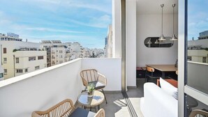 A balcony with wicker furniture, a dining table, and a sofa.