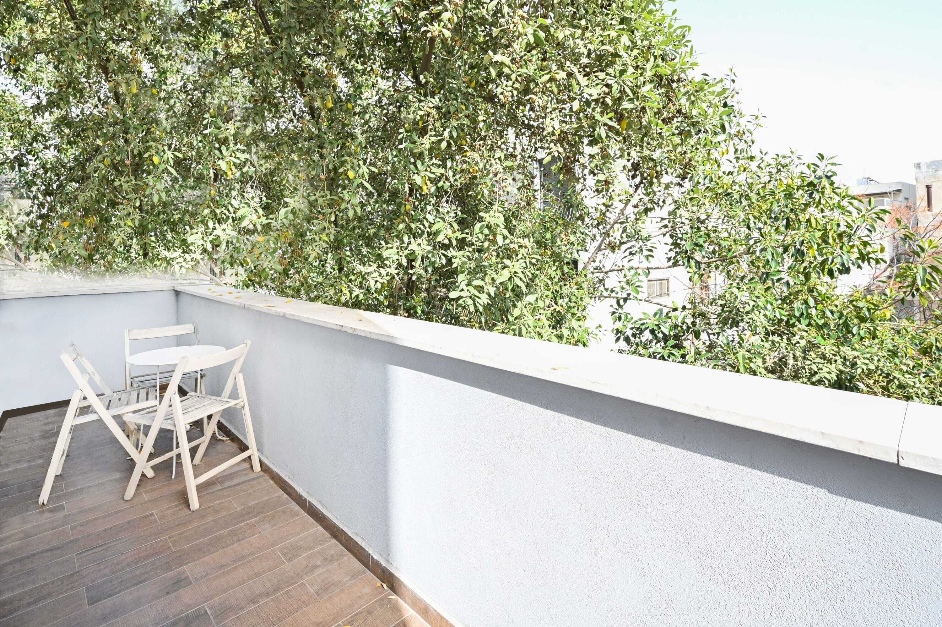 A balcony with a white railing, a small table, and two chairs.