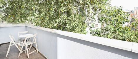 A balcony with a white railing, a small table, and two chairs.