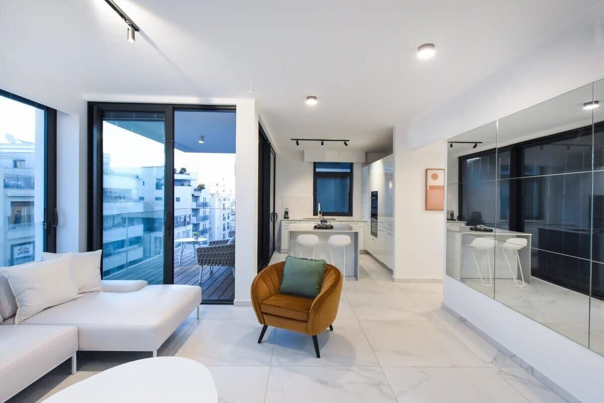 Un appartamento moderno con balcone, cucina e soggiorno con divano e poltrona.