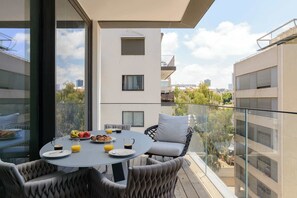 A balcony with a dining table, chairs, and a glass partition.