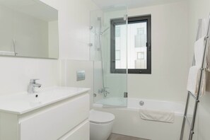 A modern bathroom with a glass-enclosed shower, a white sink, a toilet, and a bathtub.