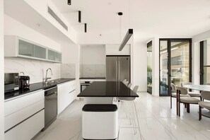 A modern kitchen with a black countertop, white cabinets, and stainless steel appliances. - Sea&City at Geula with MAMAD by HolyGuest (Tel Aviv)