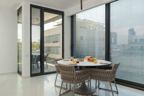 Un comedor moderno con una mesa redonda, cuatro sillas y vistas amplias a través de grandes ventanales.