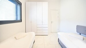 Ein Schlafzimmer mit großem Kleiderschrank, einem Bett und einem Fenster.