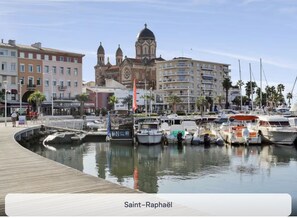 Explore the historic church with its iconic dome and bell tower, situated beside a picturesque marina with boats docked.