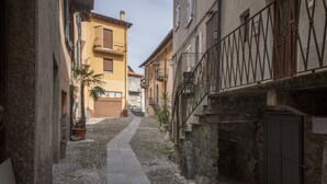 A narrow cobblestone alley between buildings with balconies and a stone staircase. - La Casa del Pescatore (Colonno)