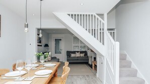 A dining area with a wooden table set for six, a staircase, and a living room in the background. - Propeller house - Wargrave near Henley (Wargrave)