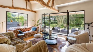 A spacious living room with a large window, a leather sofa, a glass coffee table, and a rustic ceiling. - The Lakeside Viewing Gallery (Sonning Eye)