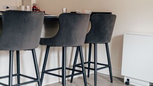 A modern kitchen with three grey bar stools, a white cabinet, and a small table with a decorative bowl. - Henley town centre with parking (Henley-On-Thames)