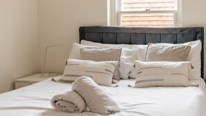 A neatly made bed with a dark headboard, white bedding, and several pillows. - Henley town centre with parking (Henley-On-Thames)