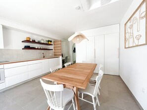 A modern kitchen with white cabinetry, a wooden dining table, and white chairs. - The Mediterranean Beach House - 100m to the Sea (Sitio de Calahonda)