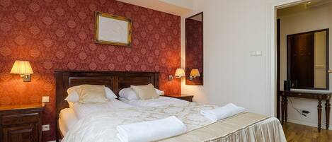 A neatly made bed with a wooden headboard, two bedside tables with lamps, and a mirror above the bed.