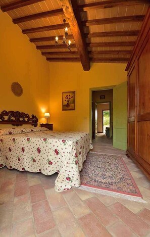 Une chambre à coucher avec un lit, une table de chevet, une lampe, un tableau et une armoire en bois.