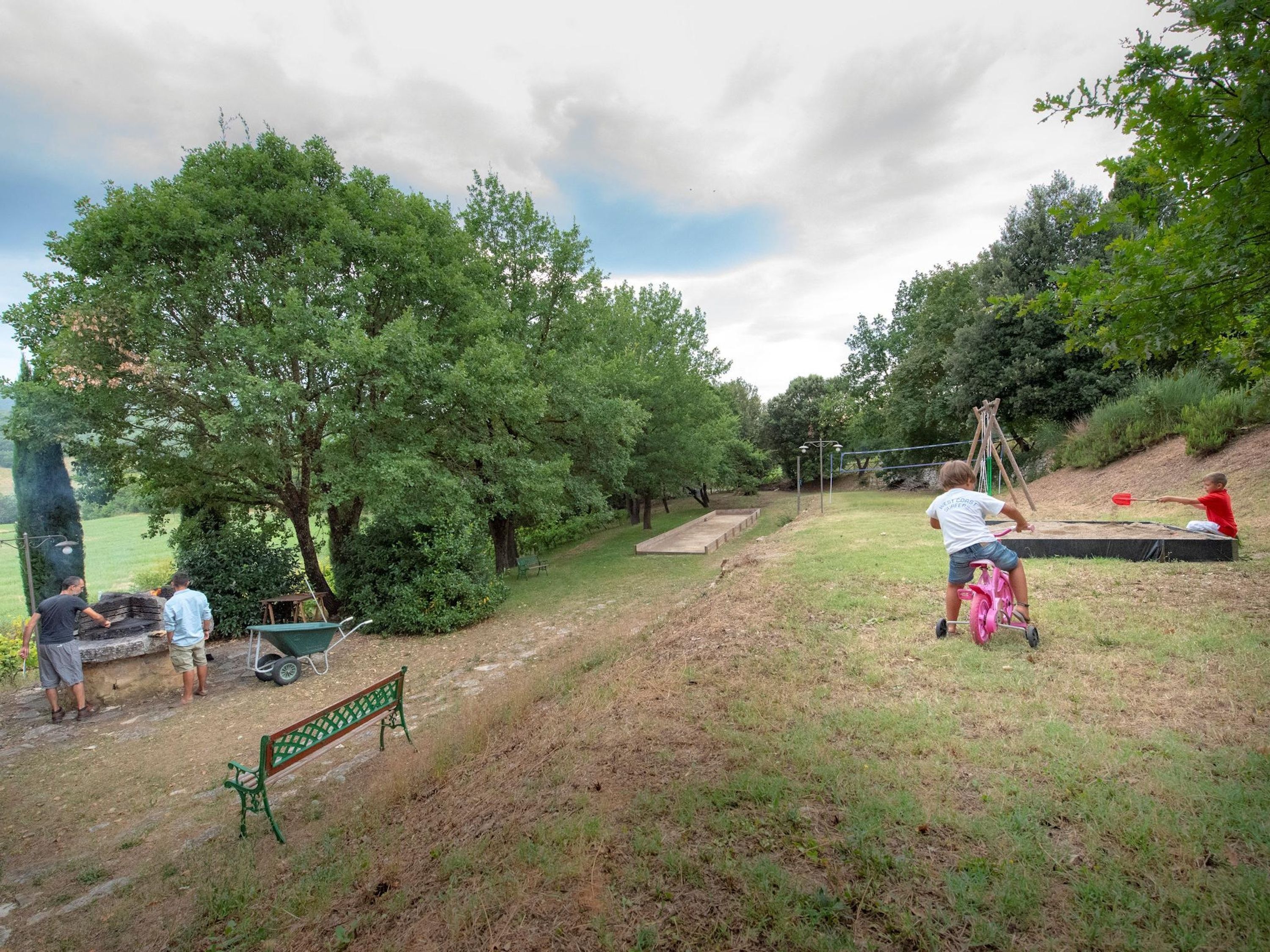 A park with a stage, trees, and a green bench.