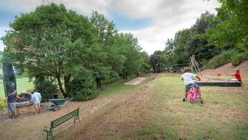 A park with a stage, trees, and a green bench.