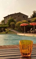 Un vaso sobre una superficie de madera, con una piscina y un edificio al fondo.