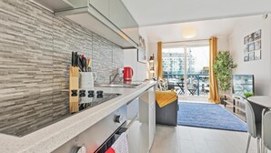 A modern kitchen with a built-in stove, a coffee maker, and a knife block. There is a balcony with a view of the marina. - On the Water -waterside Studio With Terrace Overlooking the Harbour (Brighton)