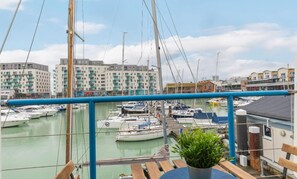 A marina with multiple boats docked, a balcony with a potted plant, and buildings in the background. - On the Water -waterside Studio With Terrace Overlooking the Harbour (Brighton)