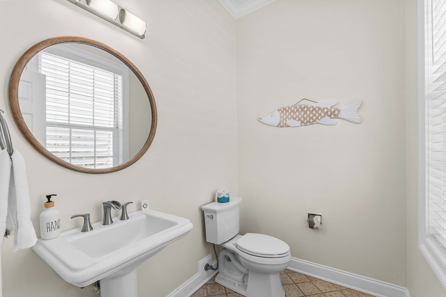 A bathroom with a sink, toilet, and a round mirror.