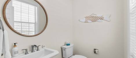 A bathroom with a sink, toilet, and a round mirror.