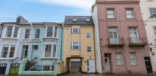 A row of three-story townhouses with bay windows, a garage door, and a small balcony on the right.