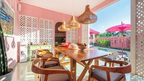 A dining area with a wooden table, wicker chairs, and hanging wicker lamps. - PinkPrivate Balangan - for Cool Adults Only (Jimbaran)
