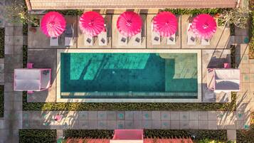 Vue aérienne d’un espace piscine avec plusieurs chaises longues et parasols.