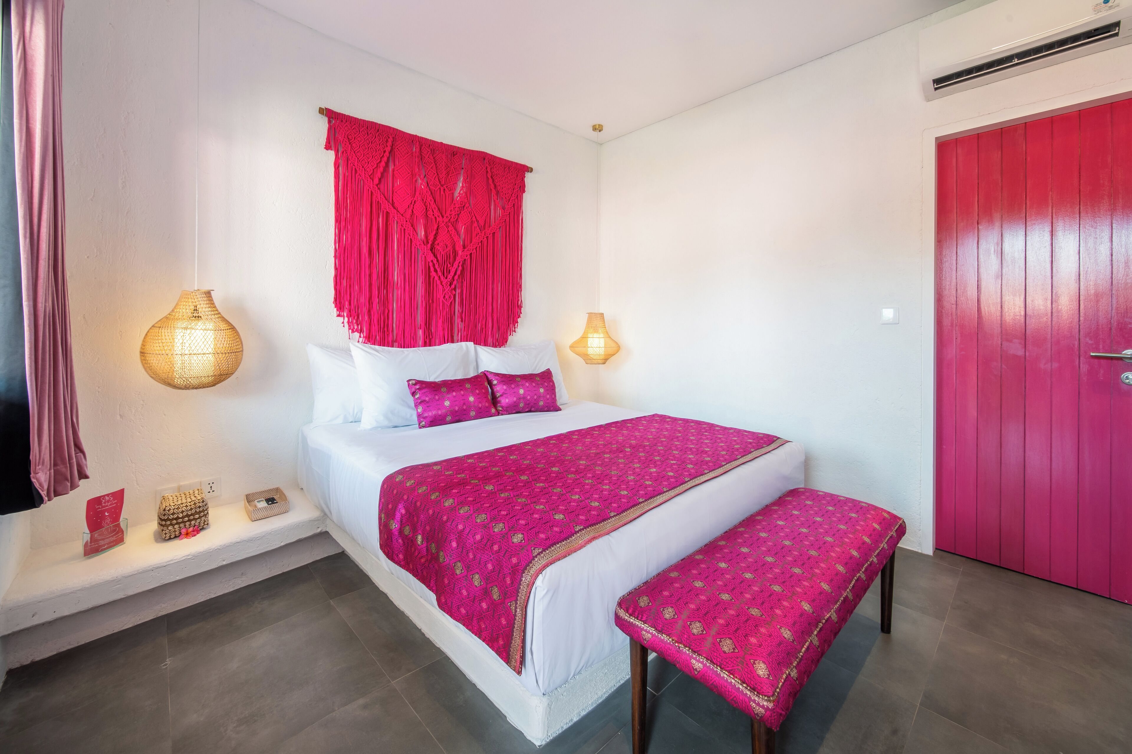 Une chambre à coucher avec un lit, une table de chevet, un banc et une porte rouge.
