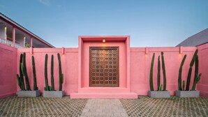 A pink building with a central door, surrounded by cacti, and a patterned floor. - PinkPrivate Balangan - for Cool Adults Only (Jimbaran)