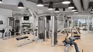 A gym with various exercise machines, benches, and a mirrored wall.