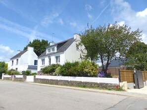 A two-story house with a white exterior, a stone wall, and a wooden fence. - Charming holiday cottage - Le Bono (Le Bono)