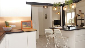 Une cuisine compacte avec un plan de travail en bois, un panier de fruits et une œuvre d’art encadrée.