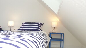 Une chambre à coucher avec un lit, deux lampes de chevet, une table de chevet et un plafond en pente.