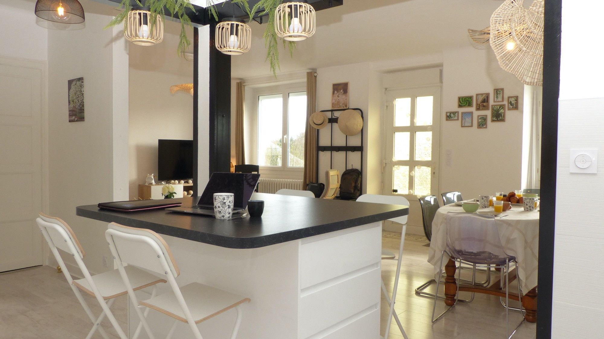 Cozinha moderna com ilha central, cadeiras brancas, mesa de jantar com toalha branca e luminárias pendentes.