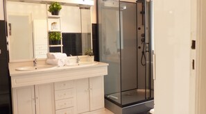 A modern bathroom with a glass-enclosed shower, a double sink vanity, and a large mirror.