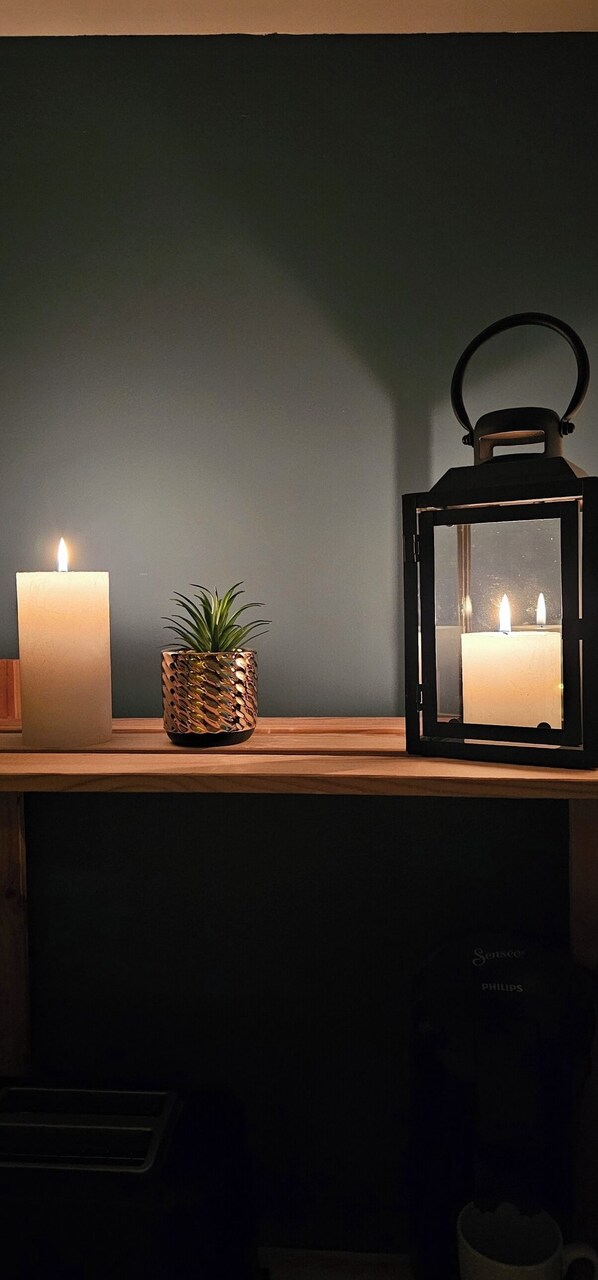 A shelf with a lit candle, a potted plant, and a lantern. - Sous les Toits -situé sur le Port de Plaisance de Saint Valery en Caux (Saint-Valery-en-Caux)