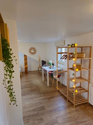 A modern interior with a wooden floor, a dining area with a table and chairs, a decorative mirror, and a wooden shelving unit with lights. - Sous les Toits -situé sur le Port de Plaisance de Saint Valery en Caux (Saint-Valery-en-Caux)