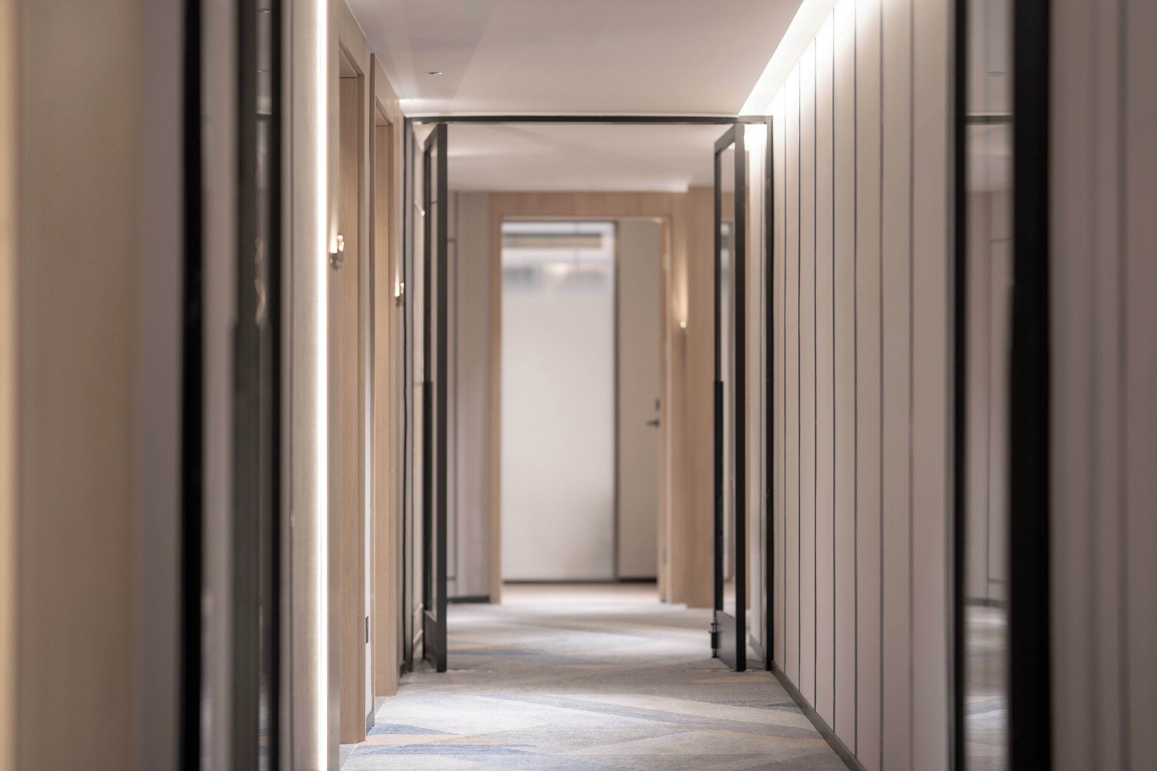 A corridor with doors on both sides, leading to a room with a large window.