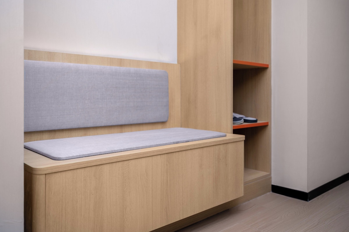 Una habitación moderna con un banco empotrado, un armario de madera y un zapatero.
