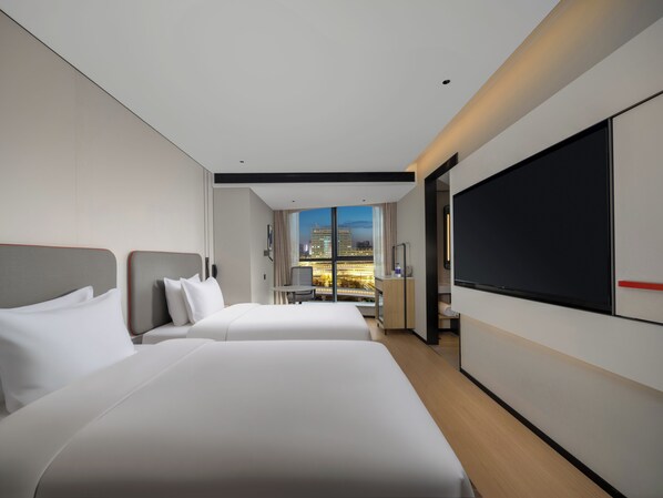 A hotel room with two beds, a TV, a desk, and a view of the cityscape. - Holiday Inn Express Luoyang Nanchang Road by IHG (Luoyang)