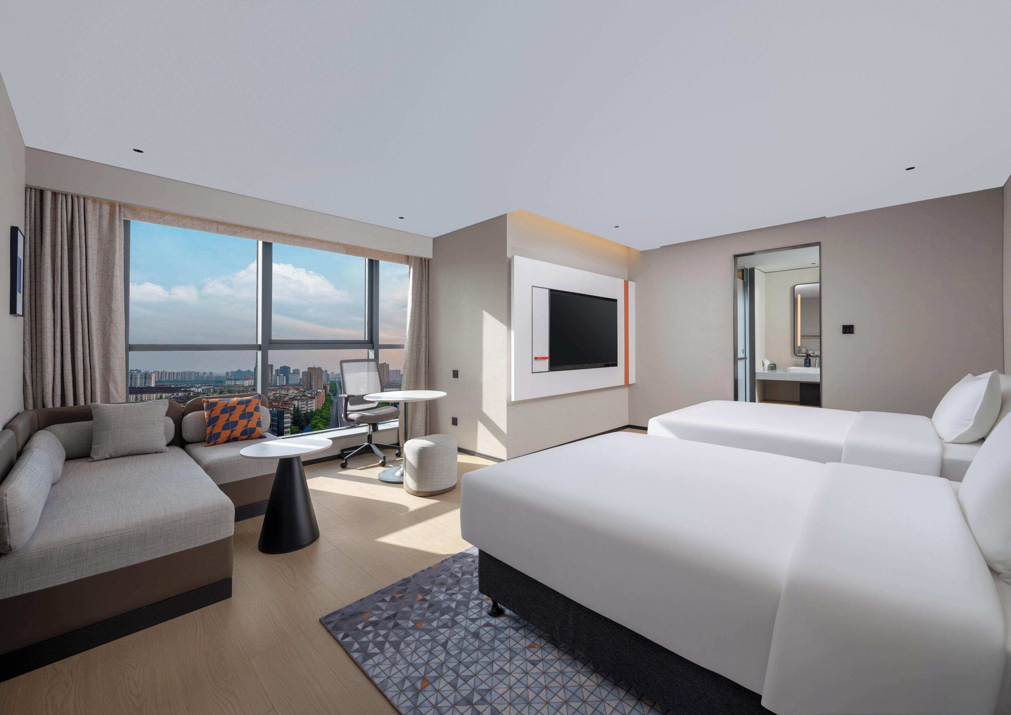 Habitación de hotel moderna con una cama grande, un sofá, un escritorio y una televisión.