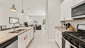 Eine moderne Küche mit Granit Arbeitsplatten, Edelstahlgeräten und Pendelleuchten.