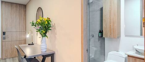 A modern bathroom with a shower, toilet, and sink. There is a wooden cabinet above the sink and a mirror above the toilet.