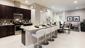 A modern kitchen with dark wood cabinets, stainless steel appliances, and a central island with bar stools.