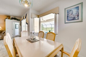 A dining area with a wooden table and wicker chairs, a ceiling fan, and a framed painting on the wall. - Kissimmee Home w/ Pool + Pond View, 5 Mi to Disney (Kissimmee)