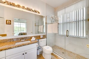 A bathroom with a granite countertop, white fixtures, a glass shower enclosure, and a large mirror. - Kissimmee Home w/ Pool + Pond View, 5 Mi to Disney (Kissimmee)