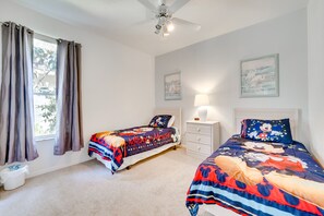 A bedroom with two beds, a ceiling fan, a nightstand with a lamp, and artwork on the walls. - Kissimmee Home w/ Pool + Pond View, 5 Mi to Disney (Kissimmee)